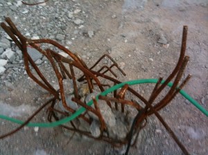 Close-up of twisted metal rods sticking out of the ground.